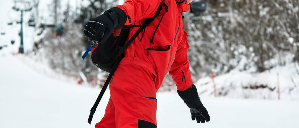 Skianzug-Herren-Test: Ein Mann fährt mit rotem Skianzug die Piste hinunter.