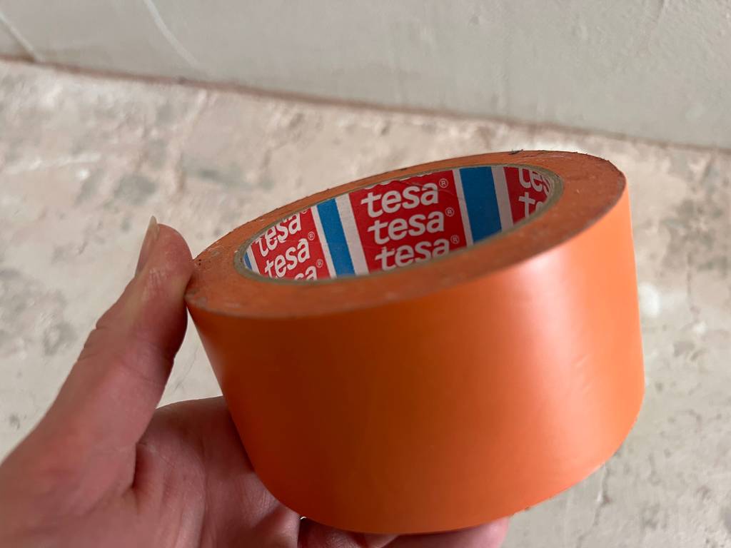 Eine Hand hält ein getestetes Malerkrepp.