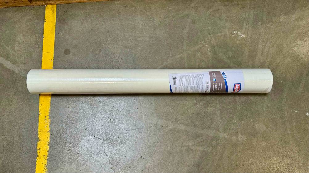 Malervlies-Tapete getestet: Eine Rolle liegt horizontal auf einem Betonboden.