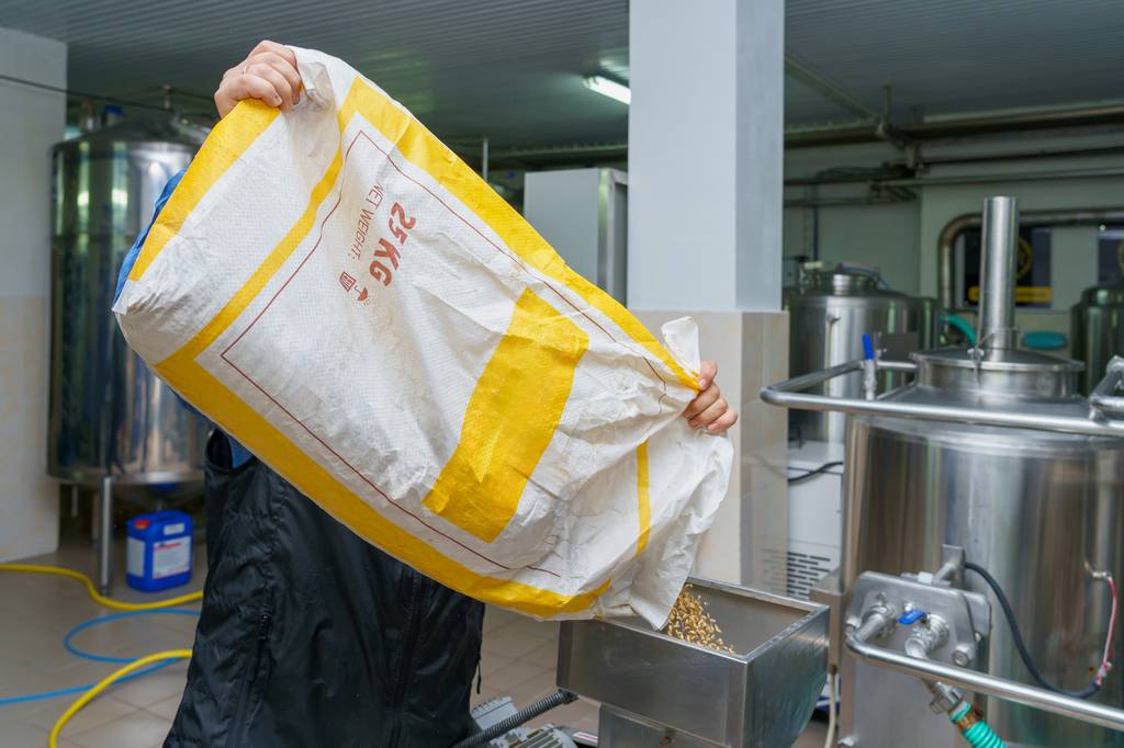 Malzmühle-Test: Ein Mann schüttet Malz in eine Malzmühle. 