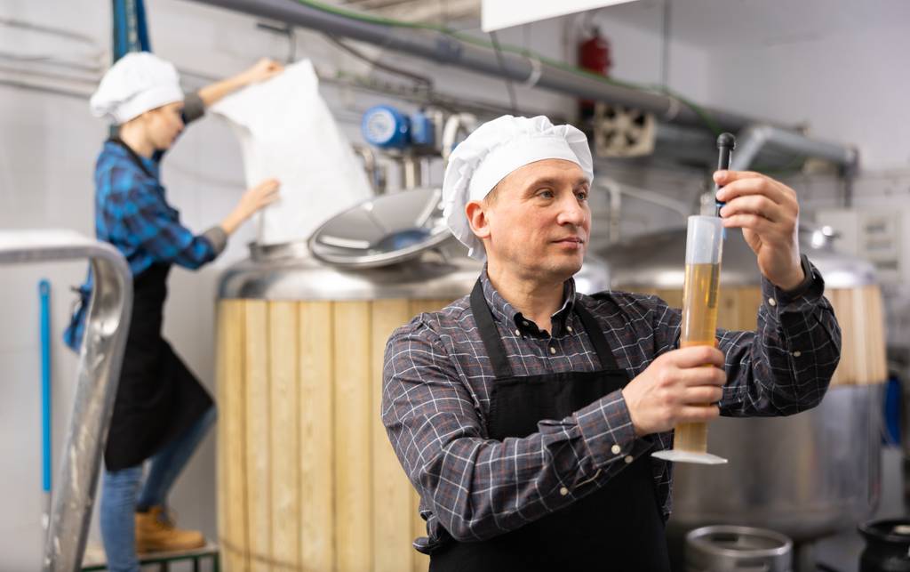 Malzmühle-Test: Ein Braumeister überprüft mit einem Hydrometer ein Braugetränk. 