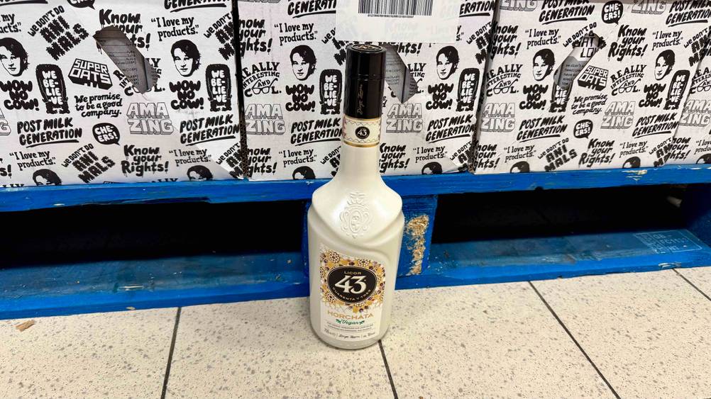 Vor einer Palette auf dem Boden steht eine Flasche des Mandellikörs im Test.