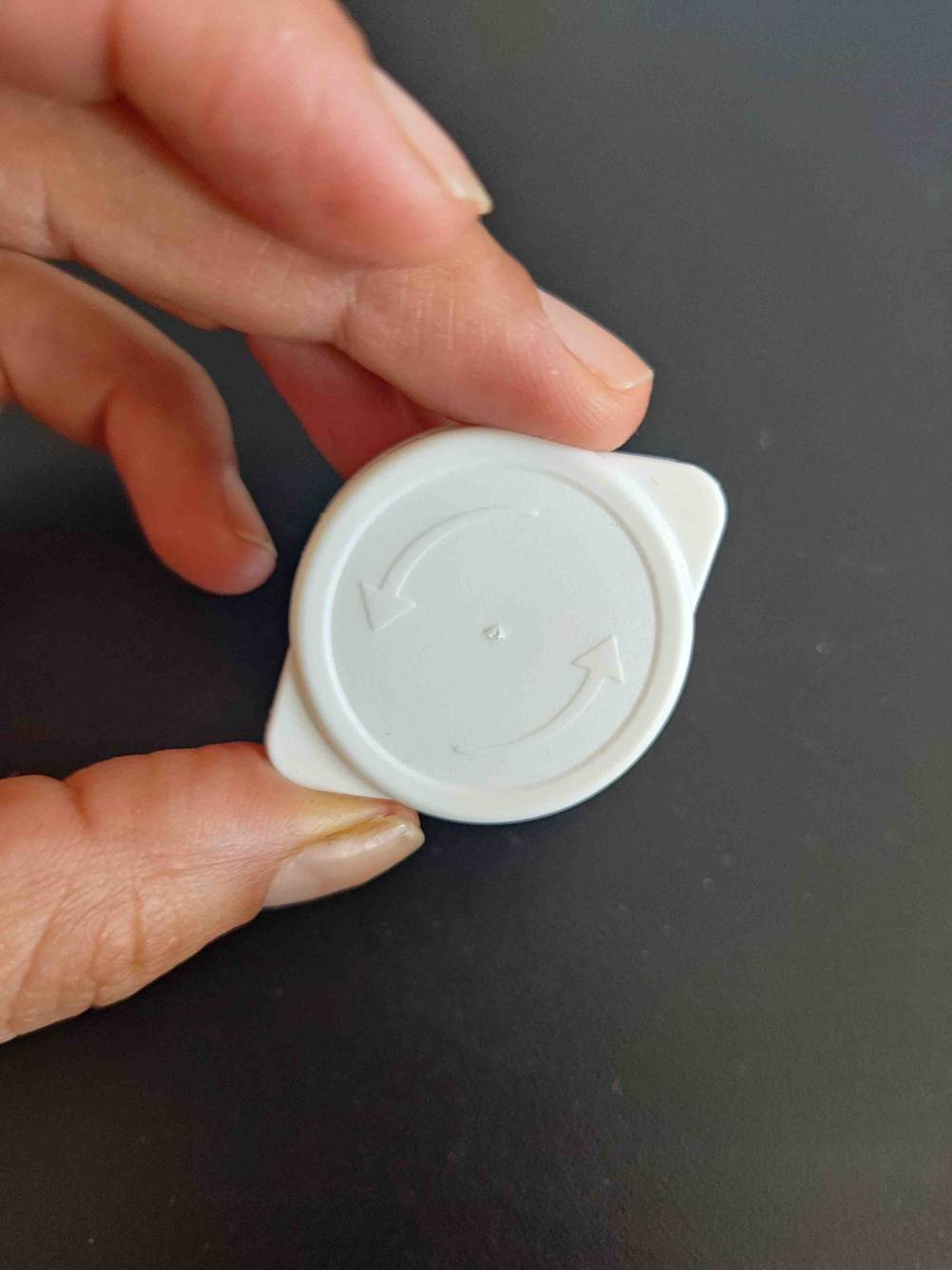 Getestet: Eine Hand hält den Deckel einer Packung Mandelmilch vor eine dunkle Fläche.