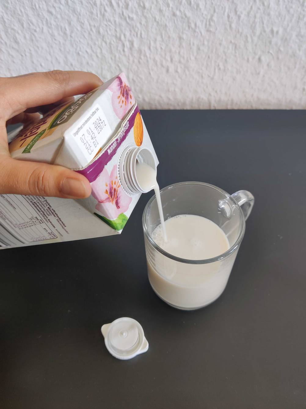 Getestete Mandelmilch wird in eine Tasse eingeschenkt. 