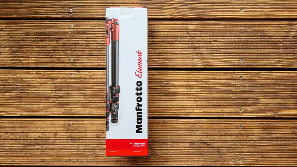 Originalverpackung eines getesteten Reisestativs liegt auf einem Holzboden.