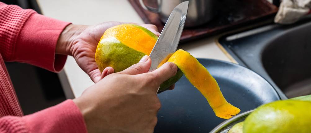 Mangoschneider-Test: Eine Mango wird mit einem Messer geschält.
