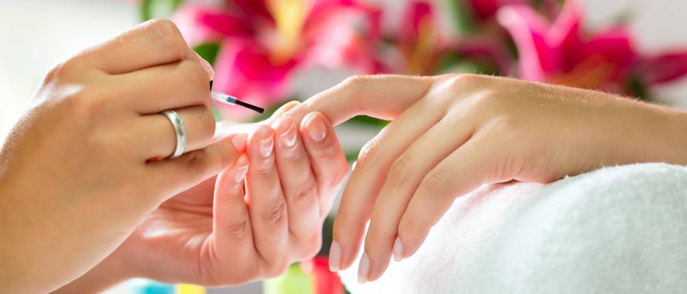 Woman in a nail salon receiving a manicure by a beautician