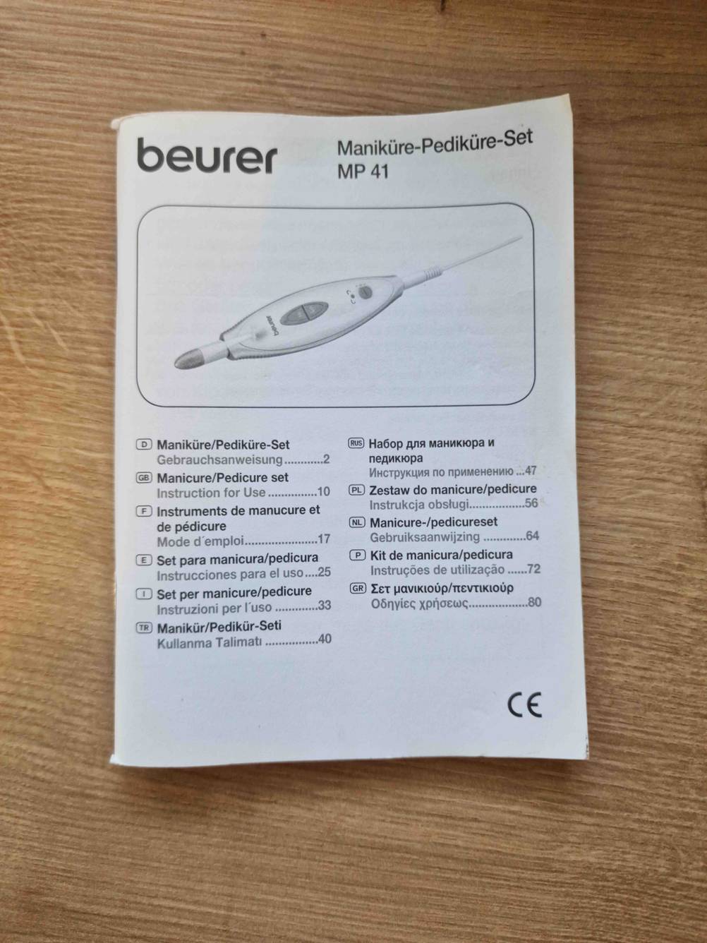 Die Bedienungsanleitung eines Maniküre-Sets auf einem Holztisch.