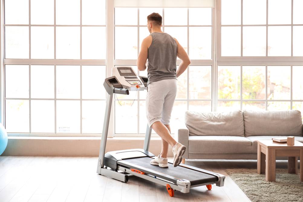 Ein Mann trainiert im Wohnzimmer auf einem getesteten Laufband mit Steigung.