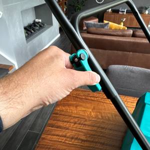 Eine Hand dreht an einer Schraube der manuellen Kehrmaschine Vonroc.