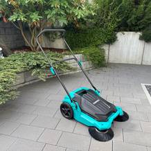 Die manuelle Kehrmaschine Vonroc steht auf Pflaster.