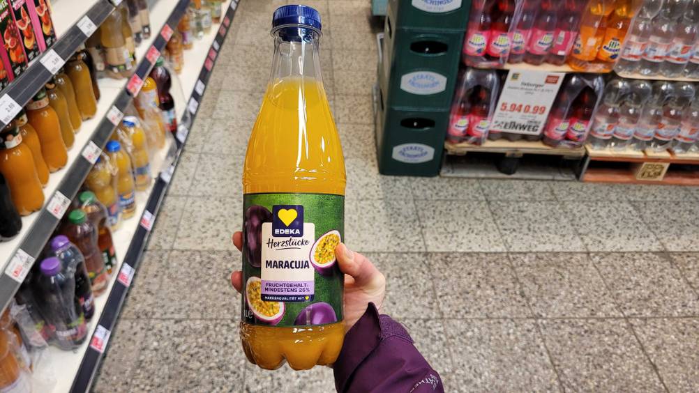 Getestet: Eine Hand hält eine Flasche Maracujasaft hoch.