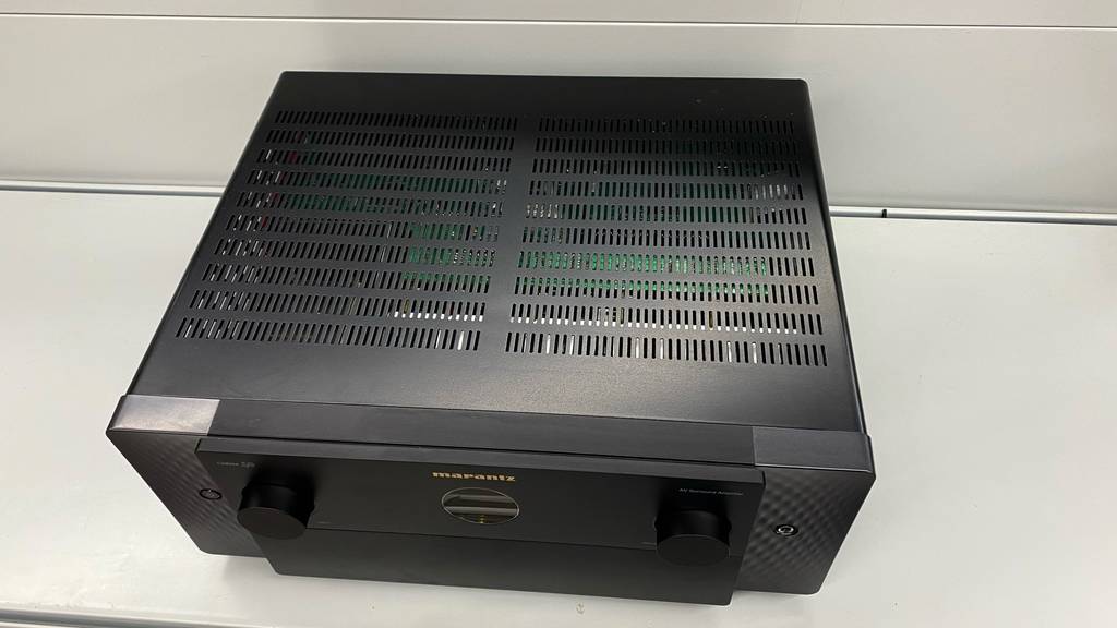 Ansicht von oben auf die Belüftungslöcher eines getesteten AV-Receivers im schwarzen Design, der auf einem weißen Regal steht.