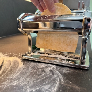 Aus der Marcato Classic Atlas 150 kommt ein dünner Teiglappen, der von einer Hand geführt wird