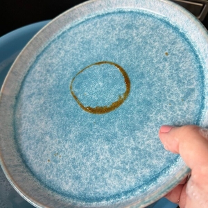 Eine Hand hält einen Teller mit eingetrockneten Ketchupresten fest.