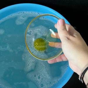 Eine Hand hält eine durchsichtige Glasschale mit Olivenöl fest.
