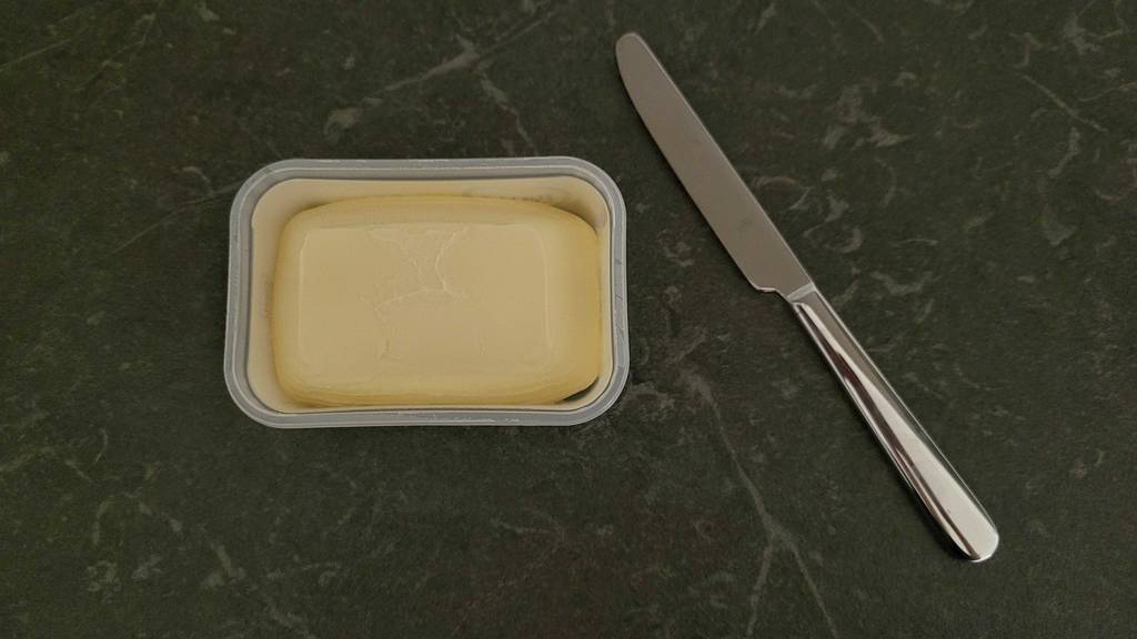 Eine Packung getestete Margarine neben einem Messer. 