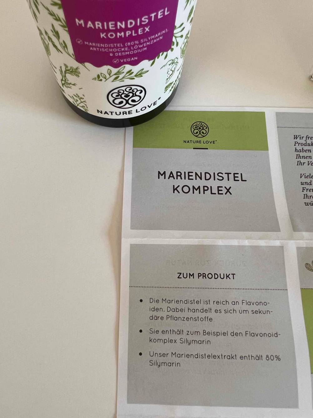 Mariendistel-Kapseln getestet: Auf dem ausgebreiteten Beipackzettel steht auf der Ecke eine Dose der Kapseln.