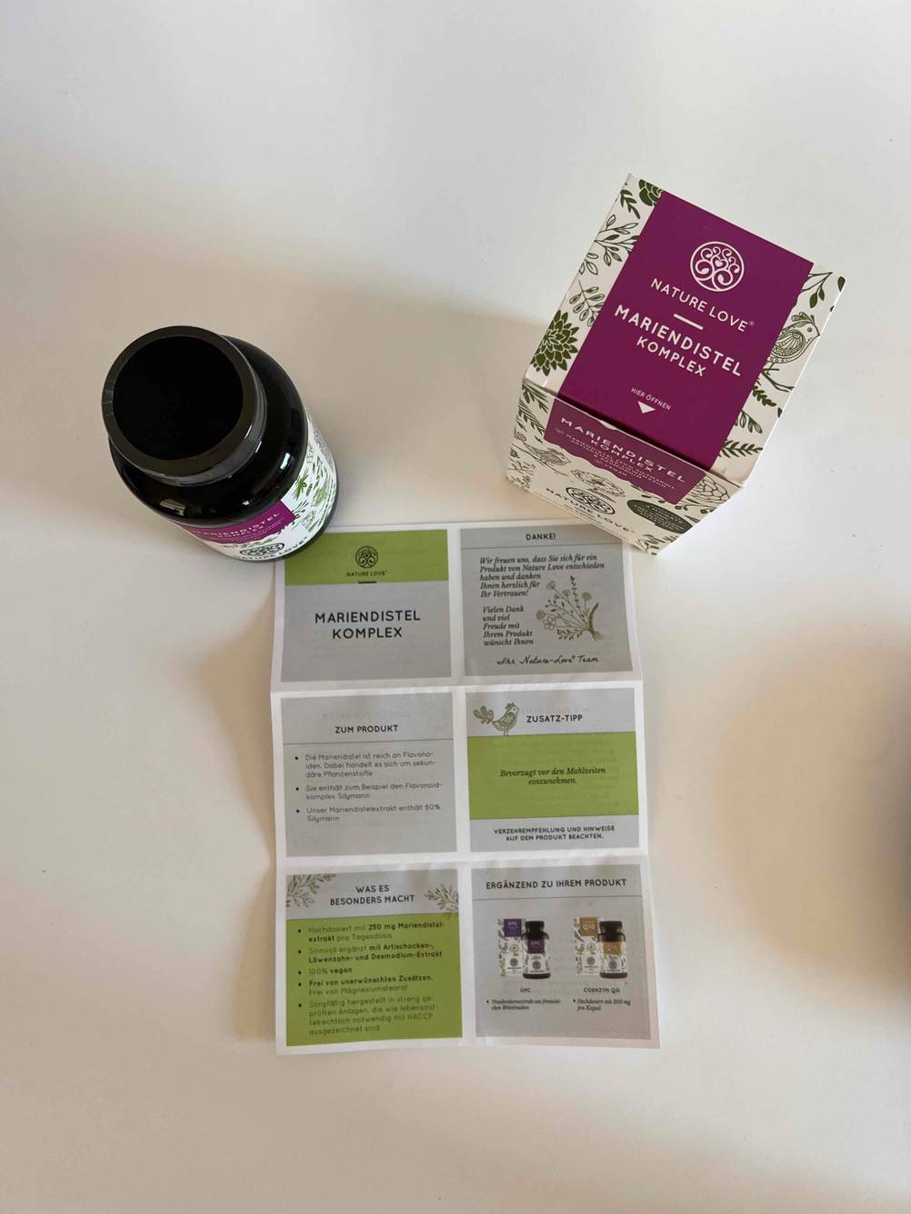 Mariendistel-Kapseln getestet: Eine Dose, die Originalverpackung und der Beipackzettel von oben auf einer hellen Fläche.