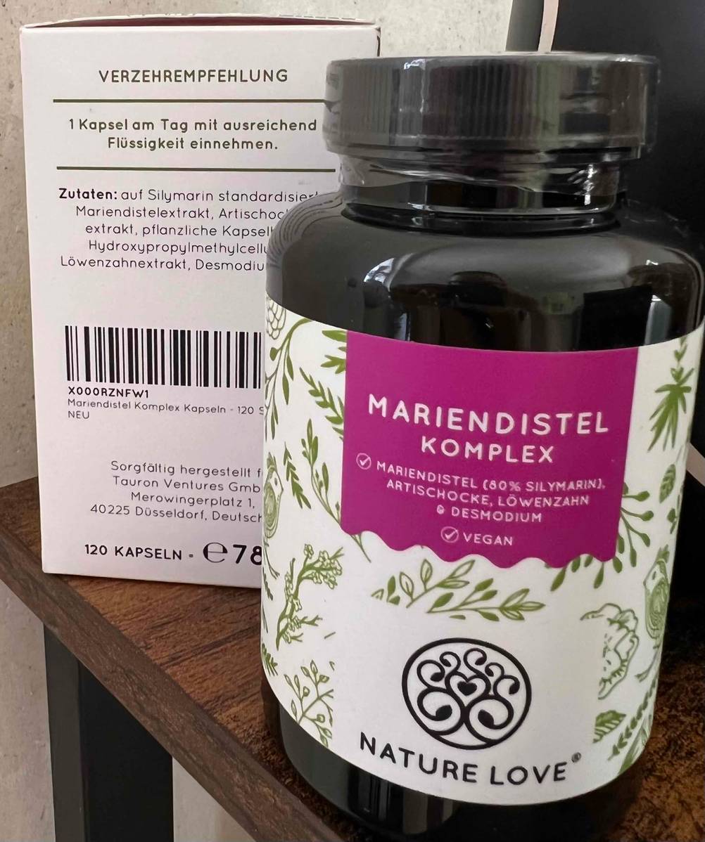 Vor einer Verpackung der gestesteten Mariendistel-Kapseln steht die Dose mit Logo.