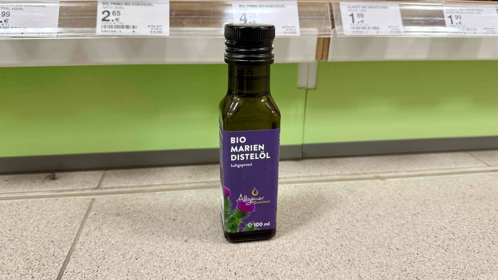 Vor einem Regal auf dem Boden steht eine Flasche des Mariendistelöl im Test.