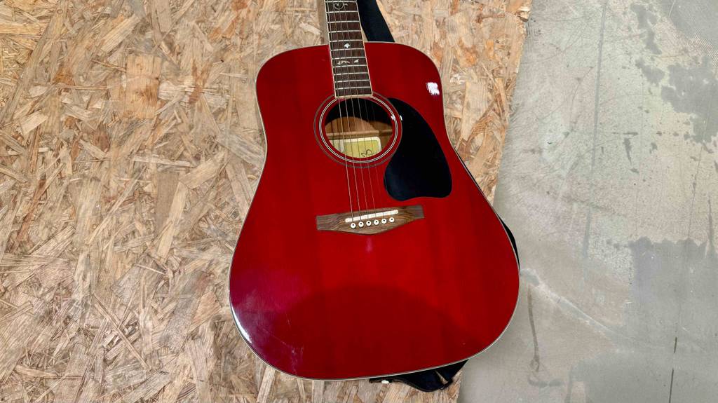 Detailansicht der Saiten einer getesteten 7-8-Gitarre, die auf einer Holzoberfläche liegt.