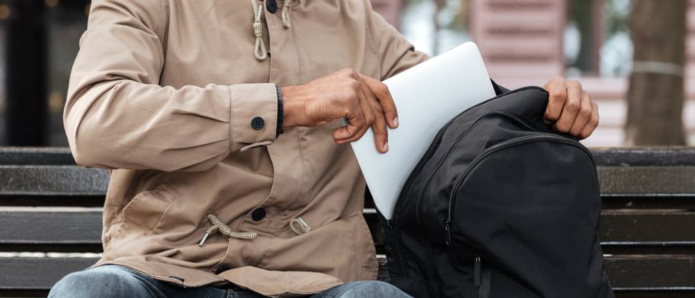 Mark-Ryden-Rucksack im Test: Mann in beiger Jacke steckt einen Laptop in einen Rucksack.