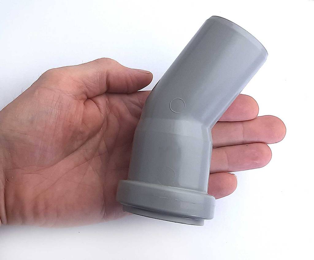 Das graue, angewinkelte PVC-Rohr im Test liegt auf einer Handfläche.