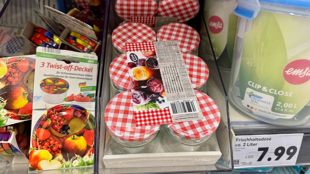 In einem Verkaufsregal befinden sich mehrere Marmeladengläser im Test neben anderen Produkten.