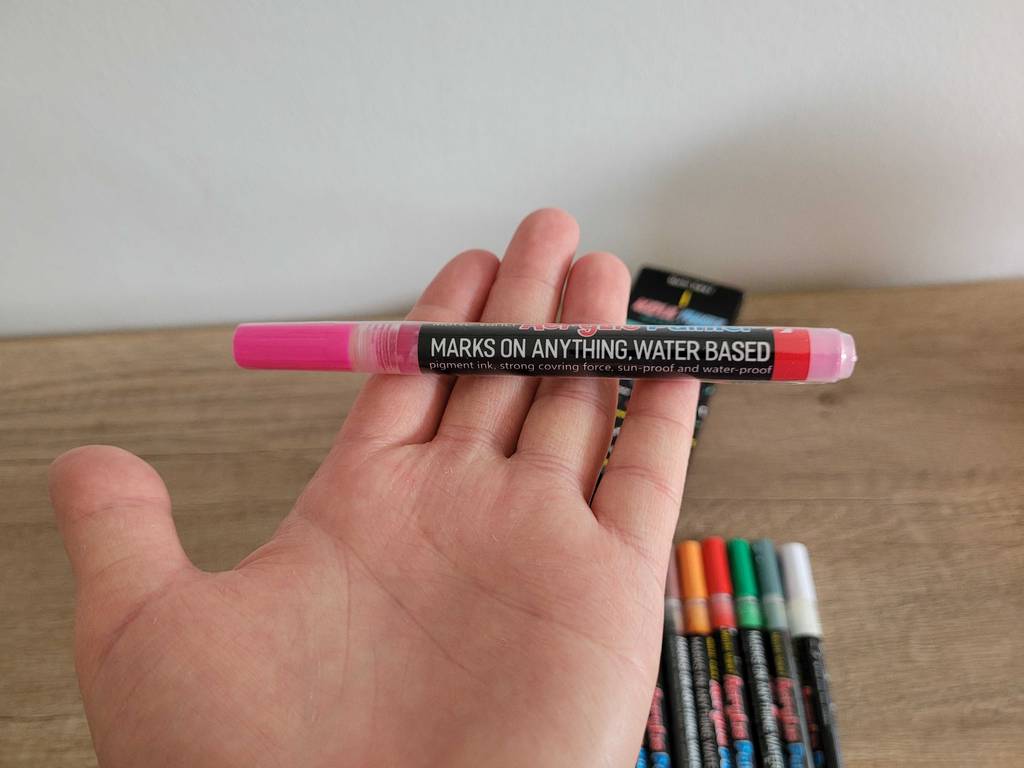 Eine Hand hält einen pinkfarbenen Acrylstift im Test nach oben.