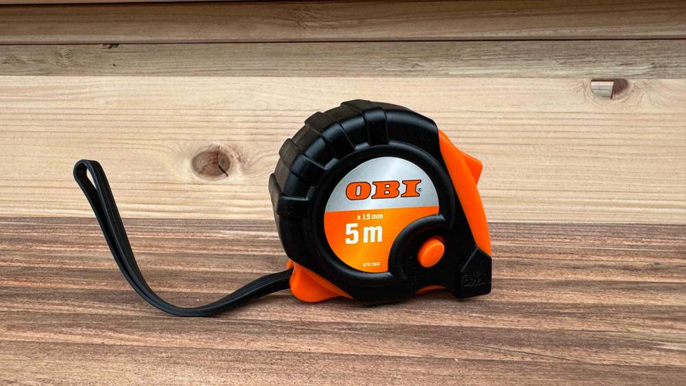 Ein getestetes Maßband 5m steht auf einer Holzfläche.