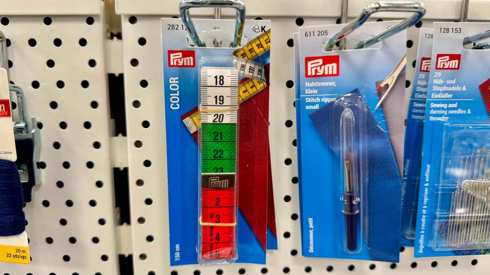 In einem Verkaufsregal hängt ein Maßband im Test neben anderen Produkten.