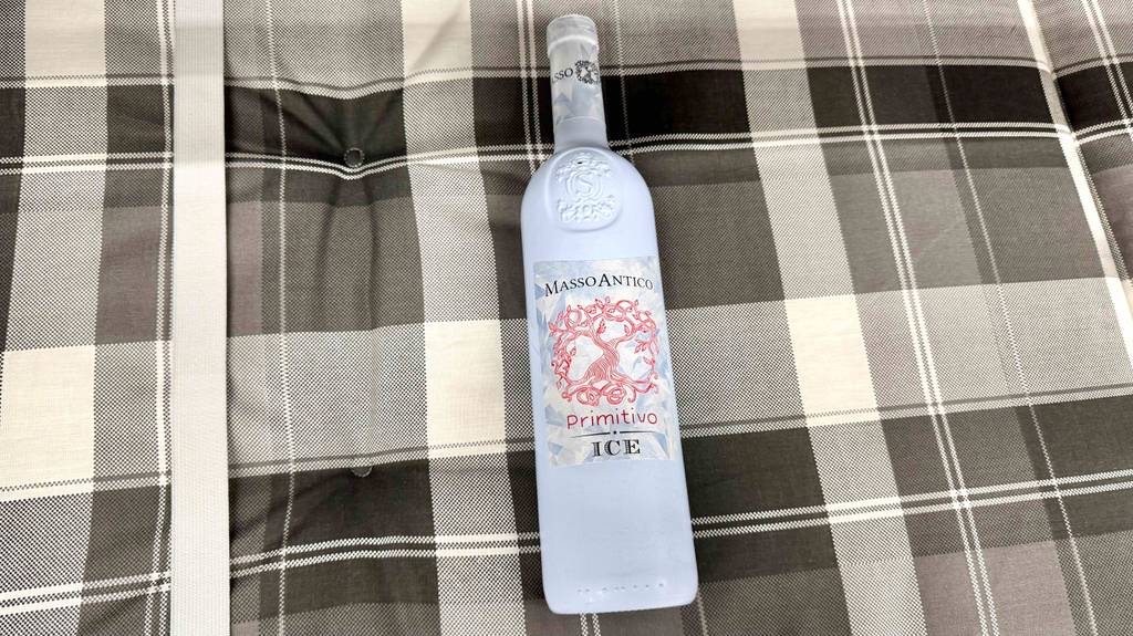 Eine Flasche getesteter Primitivo liegt auf einer schwarz-weiß-karierten Decke.