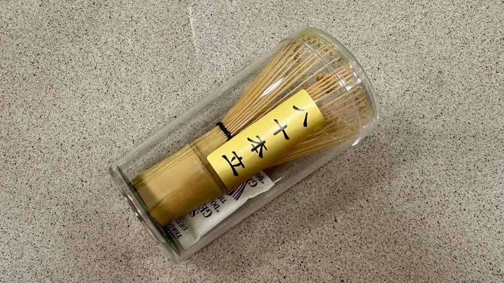 Getestet: Ein transparent verpackter Matcha-Besen auf einer beigen Fläche.