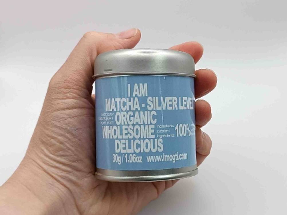 eine Dose Matcha-Tee in einer Hand