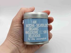 eine Dose Matcha-Tee in einer Hand