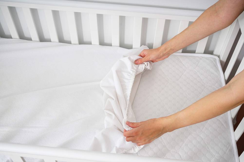 Eine Frau bezieht ein Babybett.