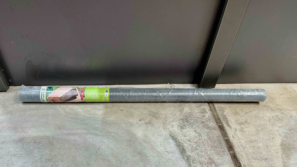 Eine Rolle des getesteten Maulwurfgitters liegt horizonal auf einen Betonboden vor einer dunklen Wand.