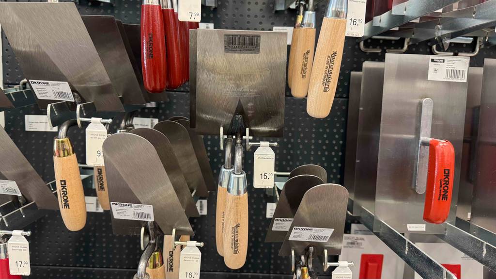 Getestet: Die Maurerkelle inklusive Holzgriff hängt neben weiteren Handwerkskellen an einem Verkaufsstand.