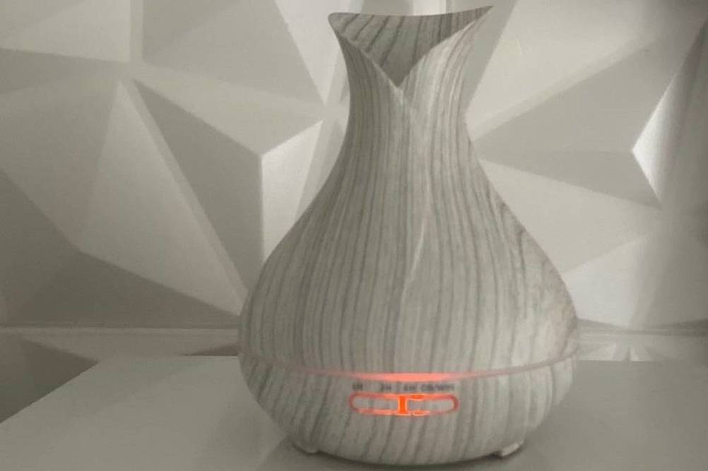 Heller, eingeschalteter und getesteter Diffuser Smart Aroma von Maxcio, der sich in einem weiß-grauen Ambiente befindet.