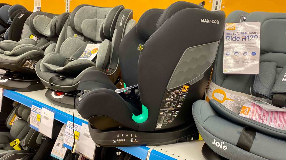 Im Test: Ein Maxi-Cosi-Kindersitz von der Seite mit Infografiken auf einem Verkaufsregal zwischen anderen Produkten.