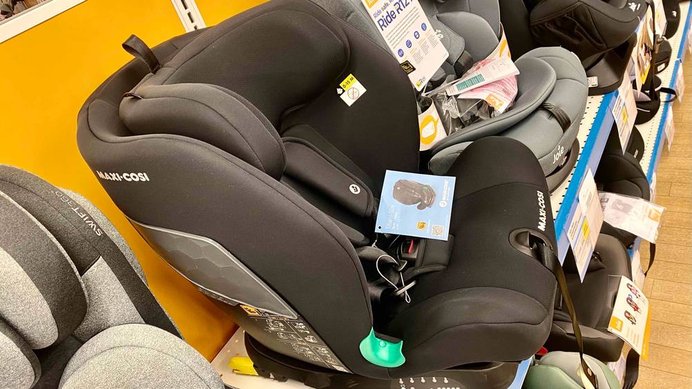Maxi-Cosi-Kindersitz-Test: Ein Sitz von der Seite zwischen anderen auf einem Verkaufstegal mit Preisangaben.