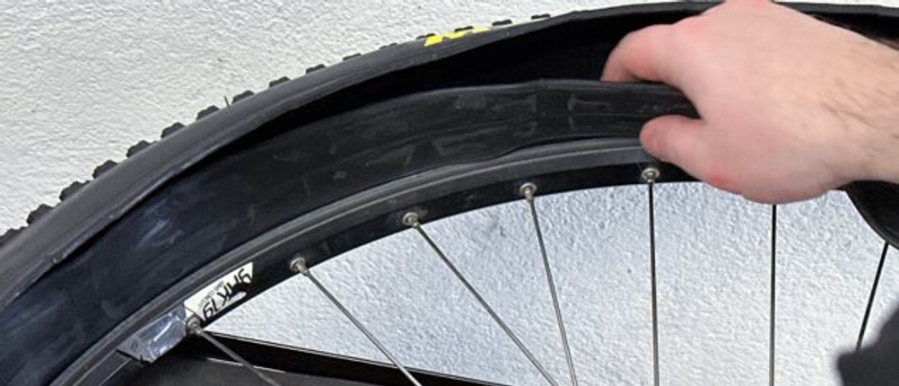 Ein Fahrradschlauch wird in den Maxxis-Cubierta-Reifen gelegt. Die Felge ist teilweise zu sehen.