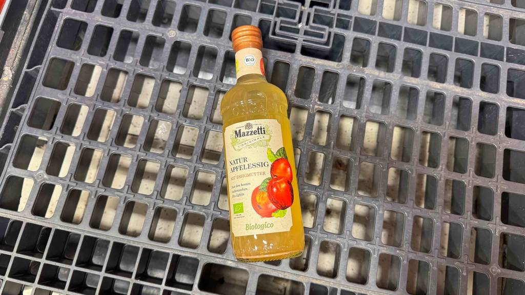 Eine Flasche Apfelessig naturtrüb liegt zum Testen auf einem Gitter.