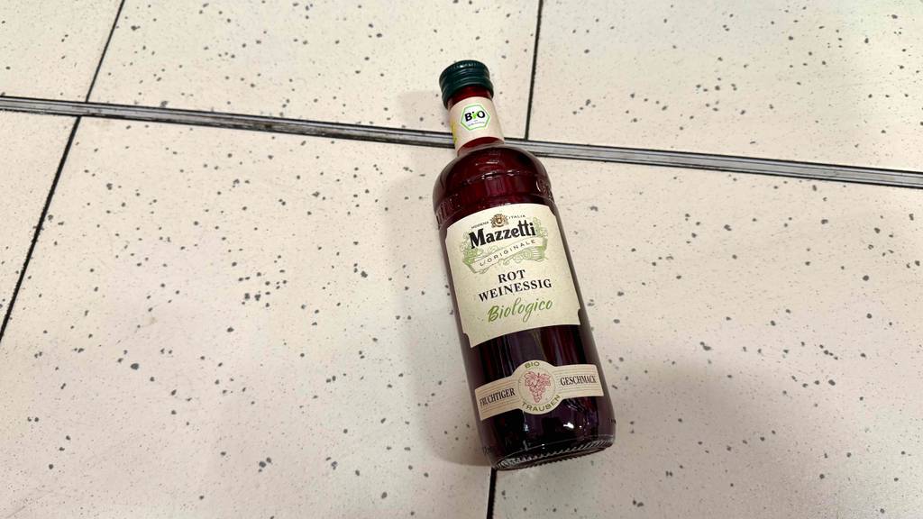 Eine Flasche Rotweinessig liegt zum Testen auf einem Gitter.