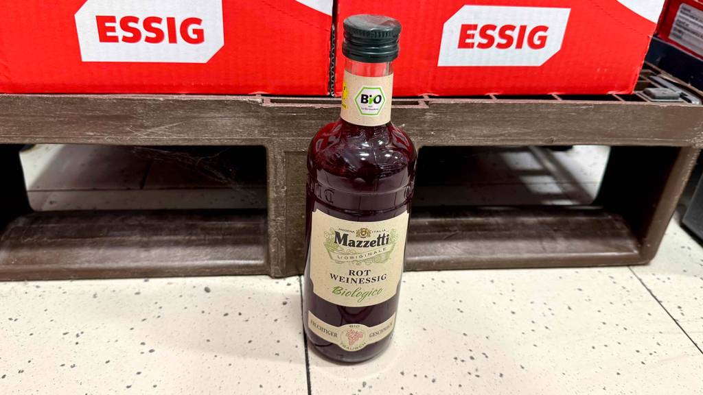 Eine Flasche getesteter Rotweinessig steht vor Kartons mit der Aufschrift Essig.