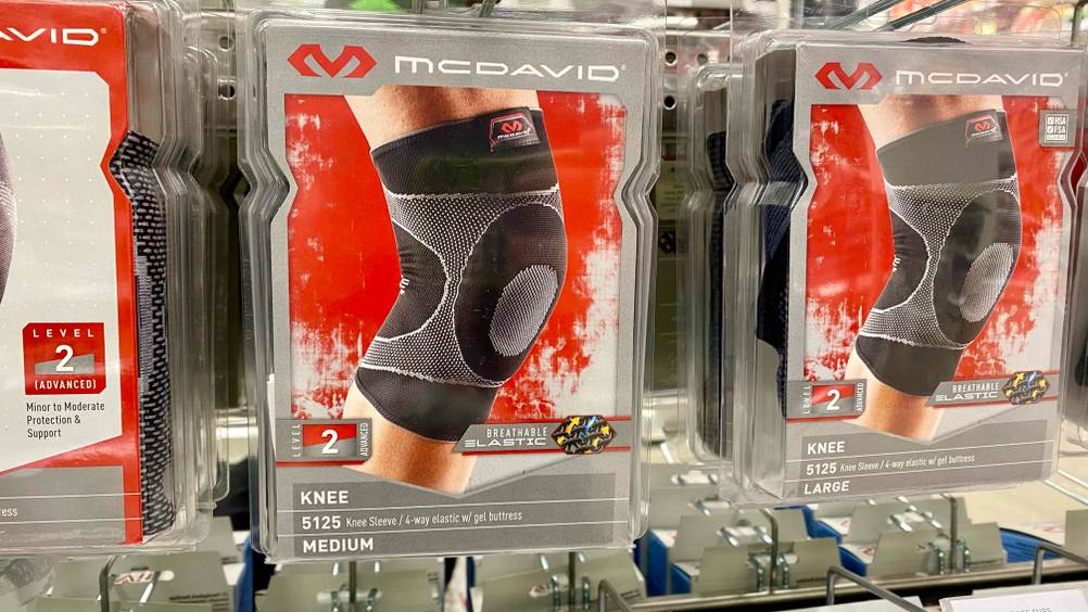 Im Test: Mehrere verpackte Kniebandagen hängen nebeneinander in einem Regal.