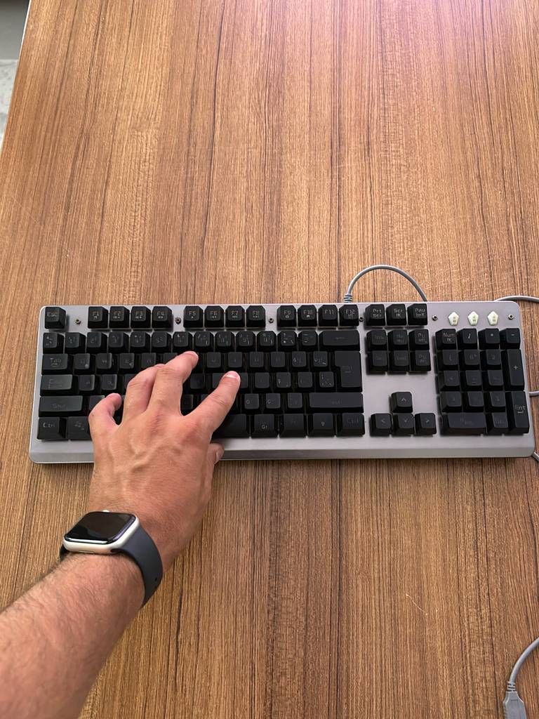 Mechanische Tastatur-Test: Eine Hand tippt auf einer Tastatur auf einem Holztisch.