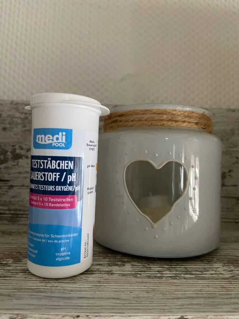 Im Test: Eine Dose Pool-Teststreifen steht neben einem Teelichtglas.