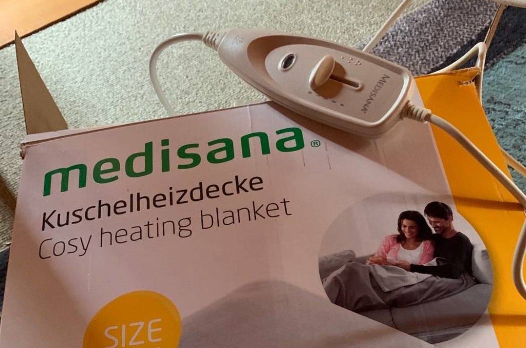 Nahaufnahme der Verpackung einer getesteten Kuschel-Heizdecke von Medisana, auf der eine weiße Fernbedienung inklusive Kabel liegt.